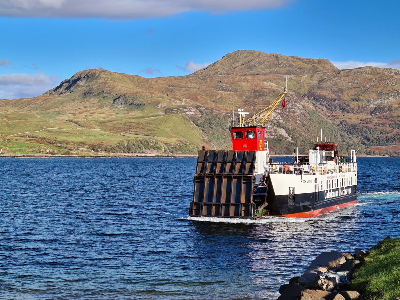 The CalMac ferry approaching Kilchoan across blue water, with the hills of Ardnamurchan behind.