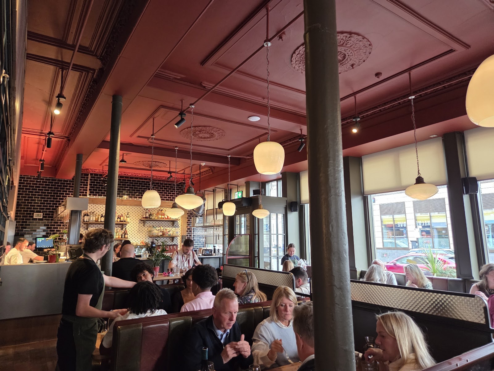 A full dining room under a red ceiling.