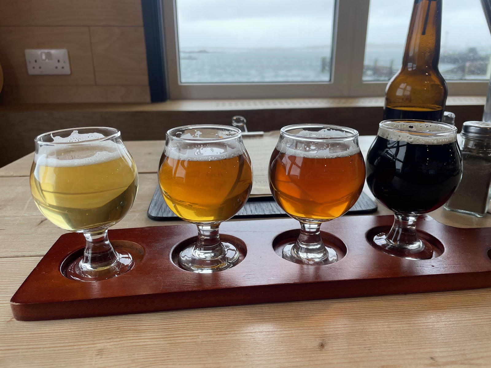 A flight of four Isle of Harris Brewery beers, from pale to dark, on a wooden board by the taproom window.