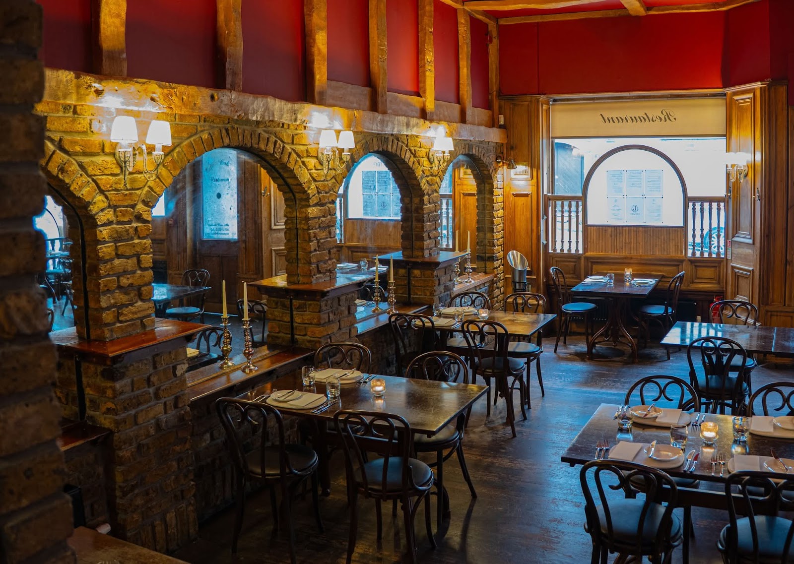 Inside Cafe Boheme, brick arches, dark wood and bentwood chairs around candlelit tables.