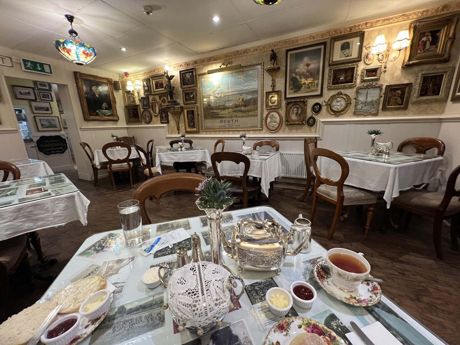 Tables laid with china in the tea room at Effie's of Perth, pictures on the walls.