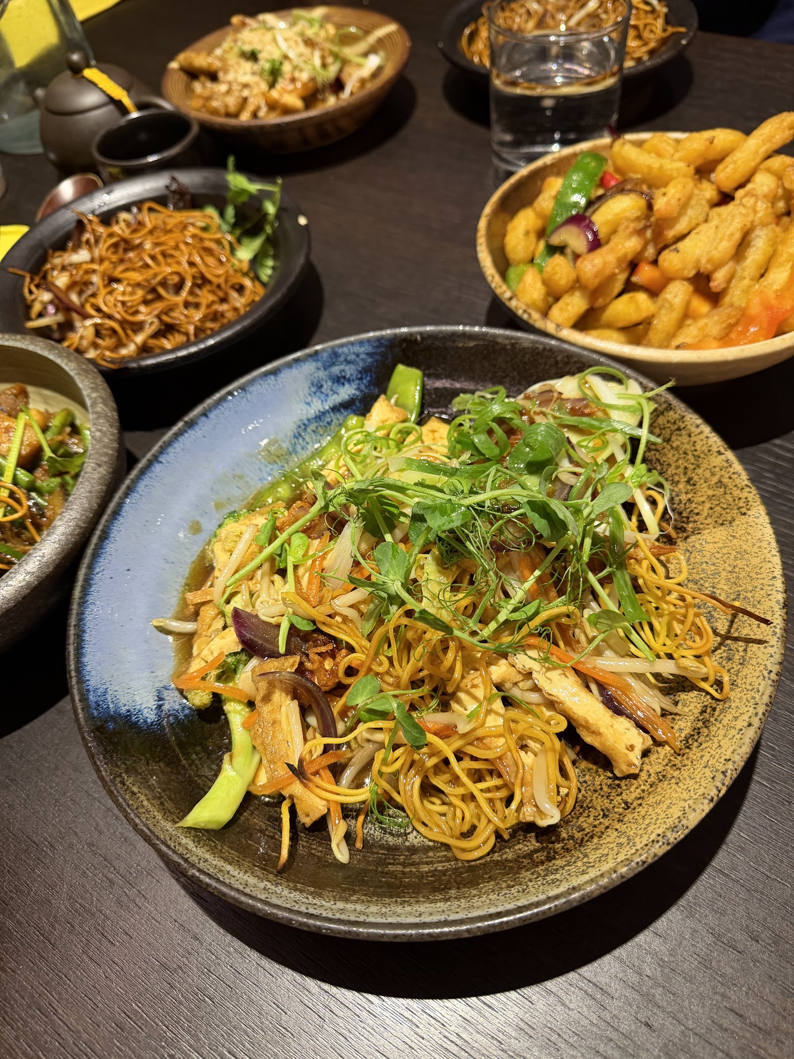 Plates of noodles and crisp bites on a table.