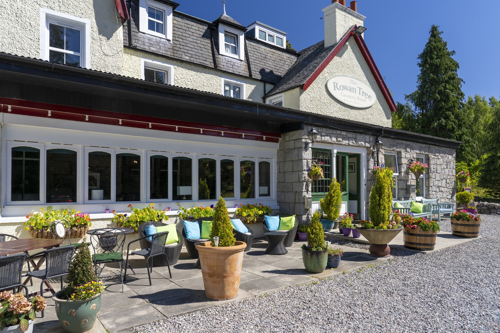 The Rowan Tree Country Hotel, with its sign on the gable and a terrace of pot plants and tables in front.