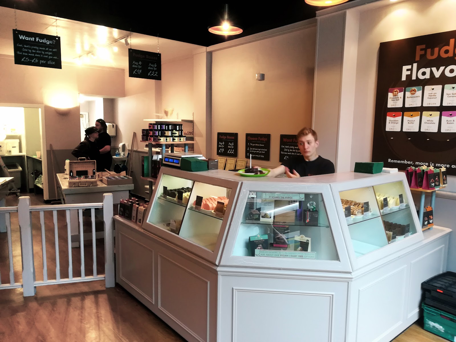 The counter at Fudge Kitchen on the Royal Mile, with fudge under glass and staff behind.