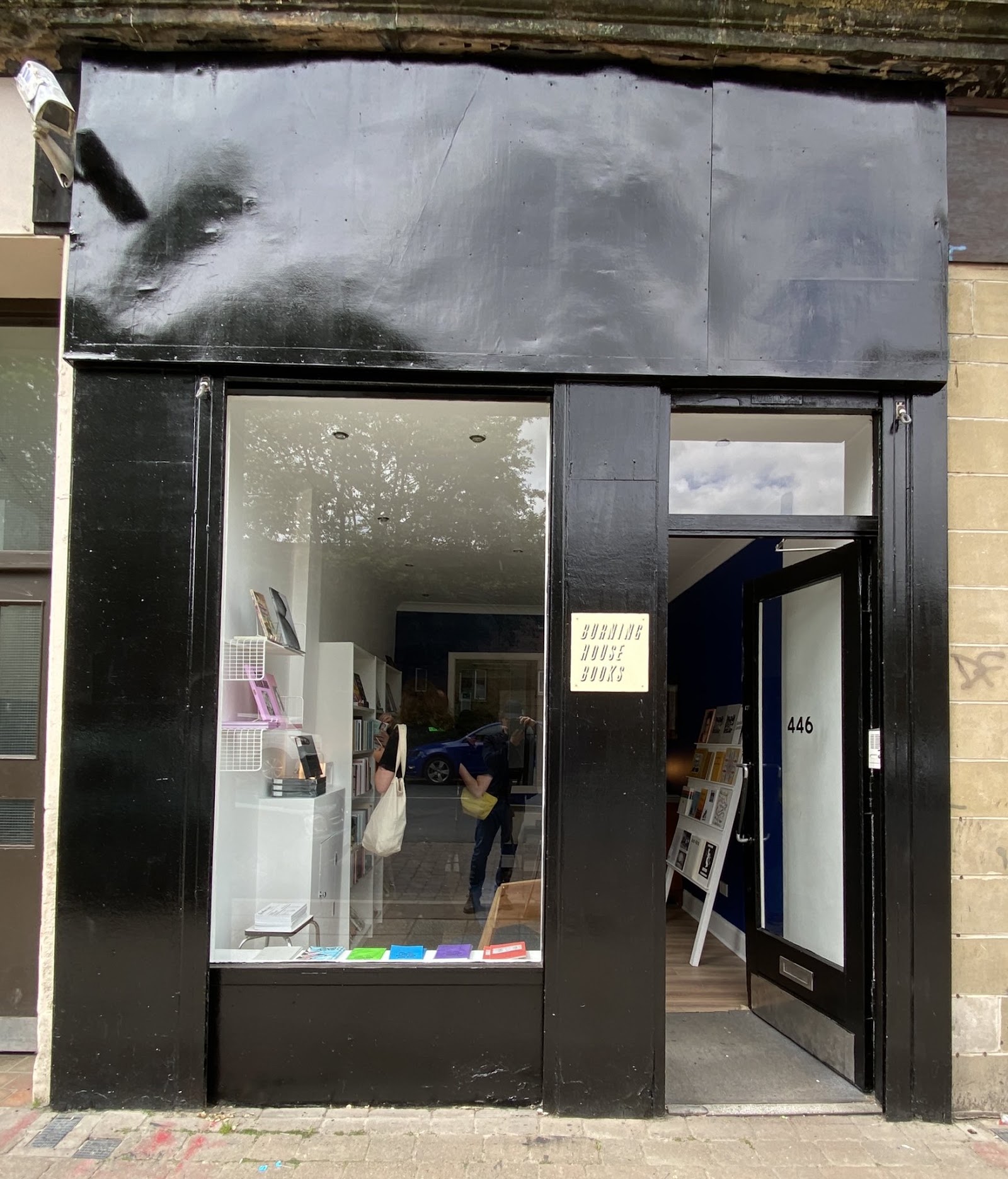 The black-painted front of Burning House Books at 446 Cathcart Road, its door open and a bright white room of books and shelves through the window.
