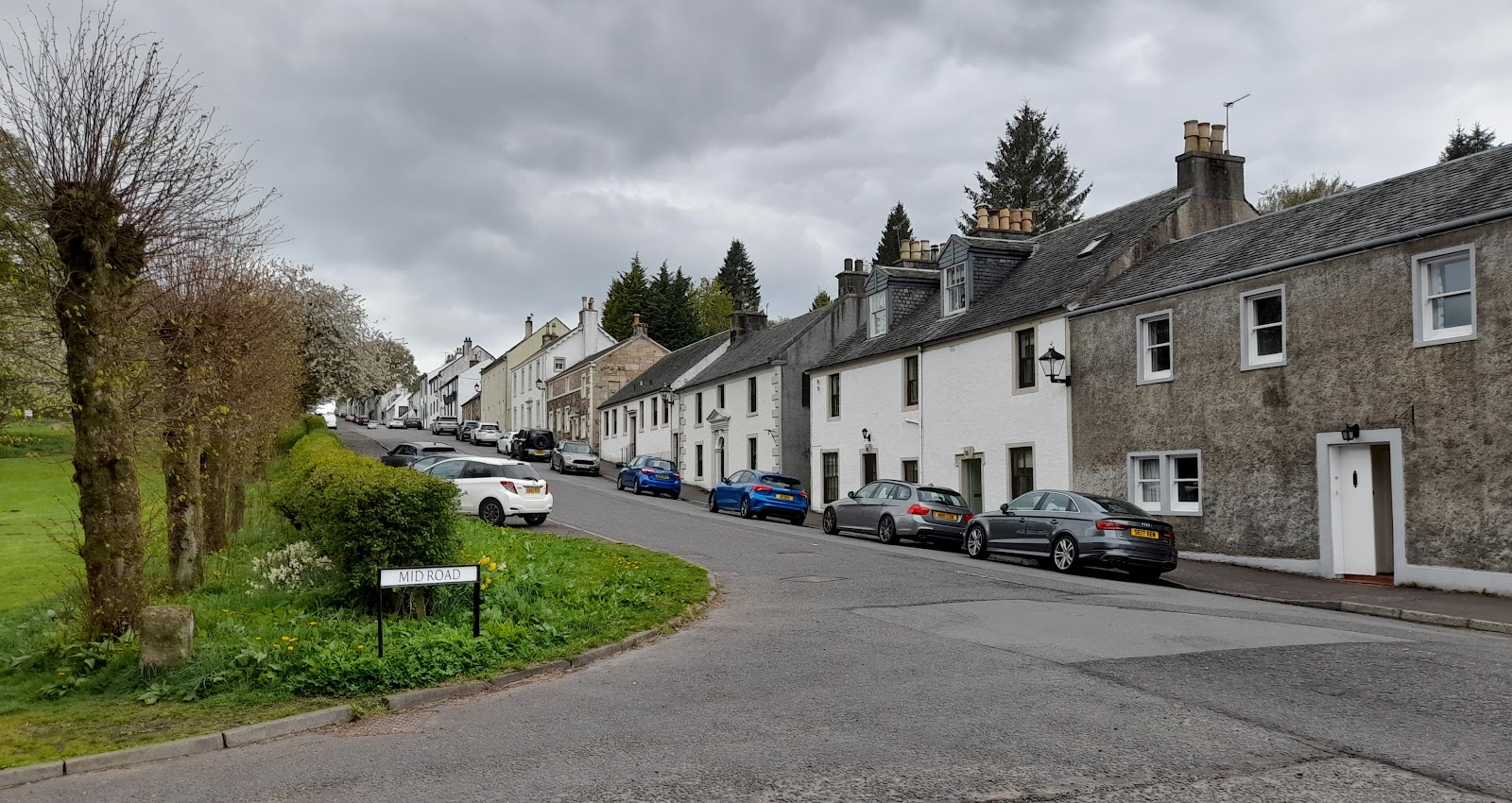 Polnoon Street in Eaglesham, its whitewashed and stone cottages curving uphill beside a line of trees.