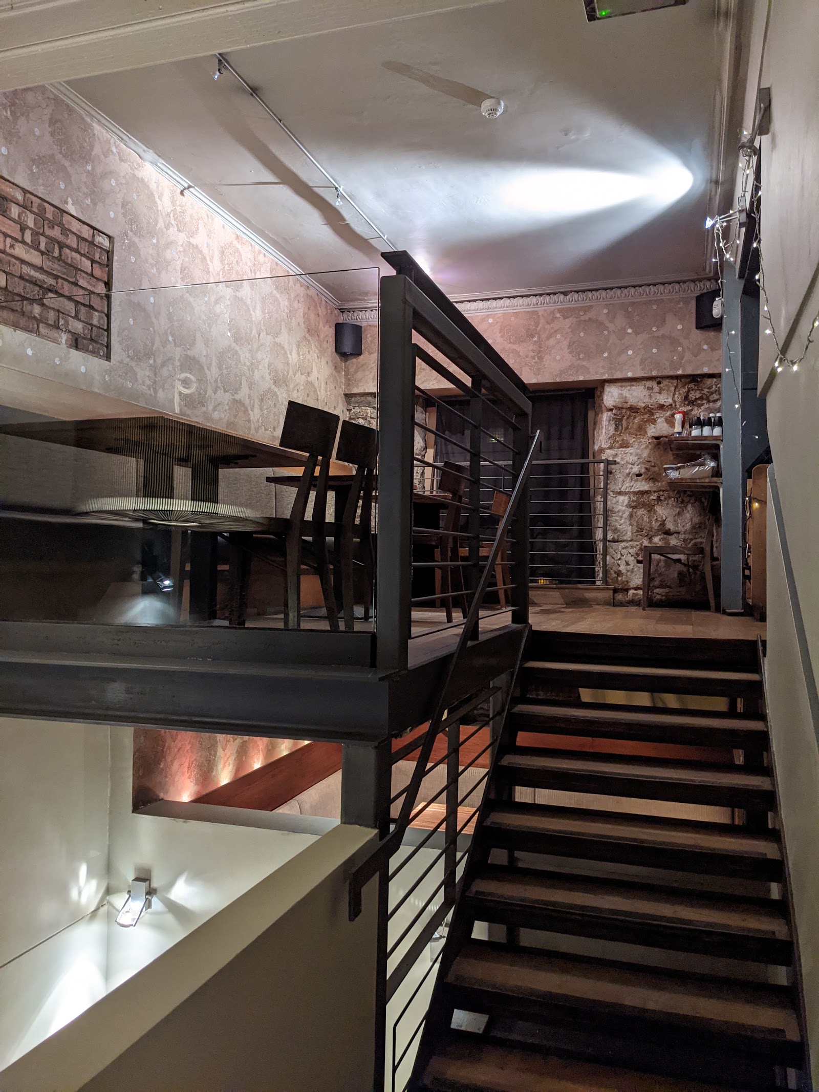A metal staircase up to the mezzanine against a brick wall.