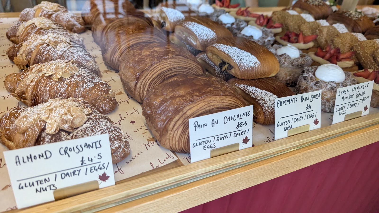 The counter at Maple Leaf Bakery in Govan: almond croissants, pain au chocolat and other pastries, each with a handwritten card.