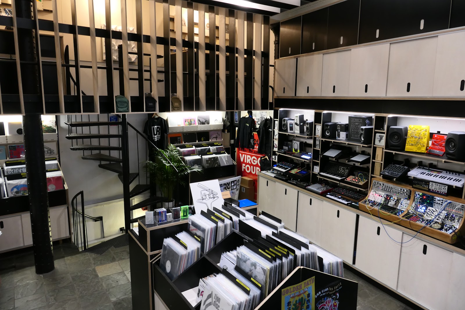 Inside Rubadub on Howard Street: racks of records in the middle of the floor, synths and drum machines on the shelves, and a spiral stair up to the gallery.