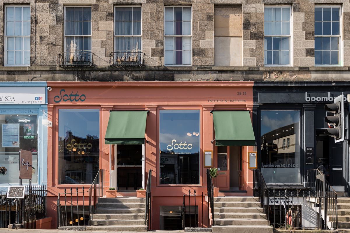 The coral-pink shopfront of Sotto on Deanhaugh Street in Stockbridge, with green awnings, its name in the windows and steps up to the door.