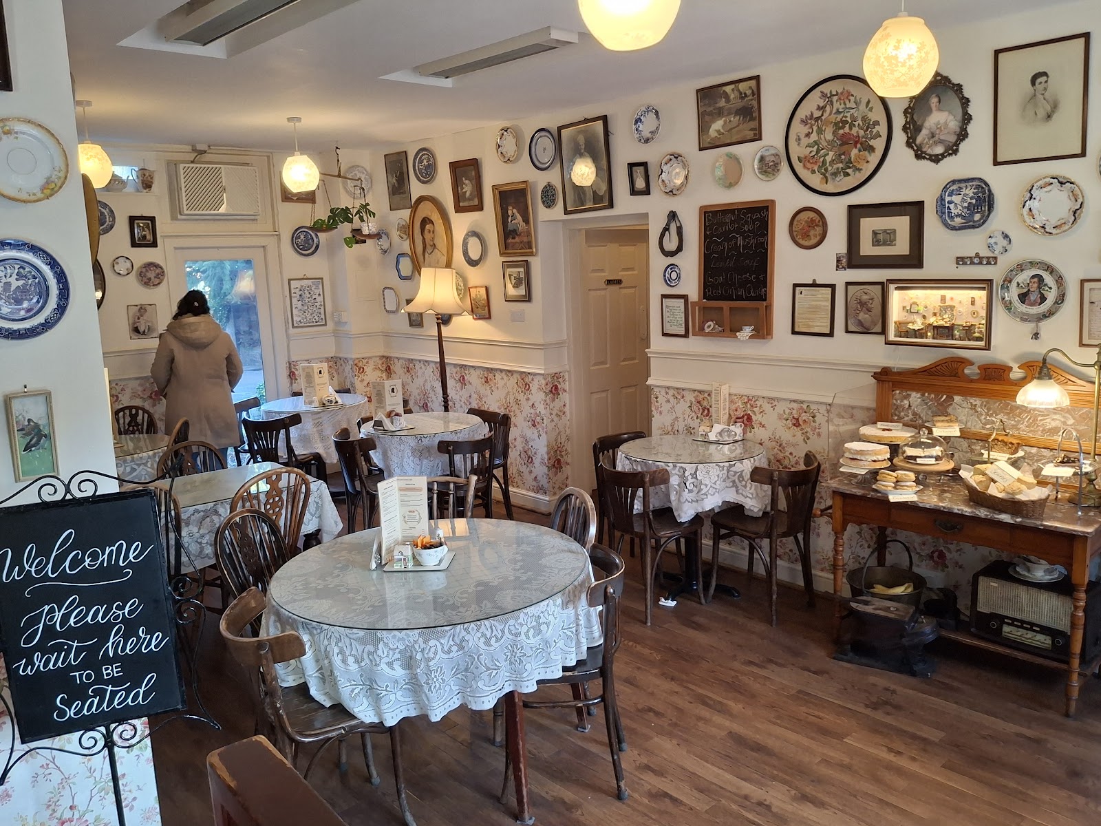 The dining room at Clarinda's Tearoom, its walls hung with plates and pictures over lace-covered tables.