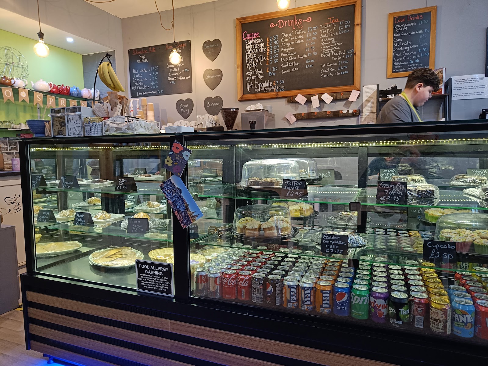 The counter of cakes and bakes under chalkboard menus at Tarland Tearooms.