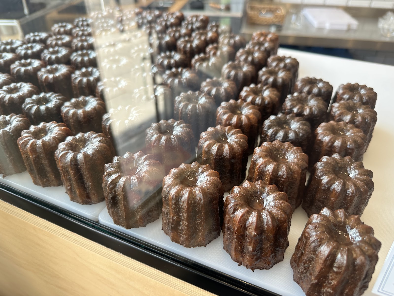 Rows of dark, fluted canelés in the glass counter at Project Canelé on Dundas Street.