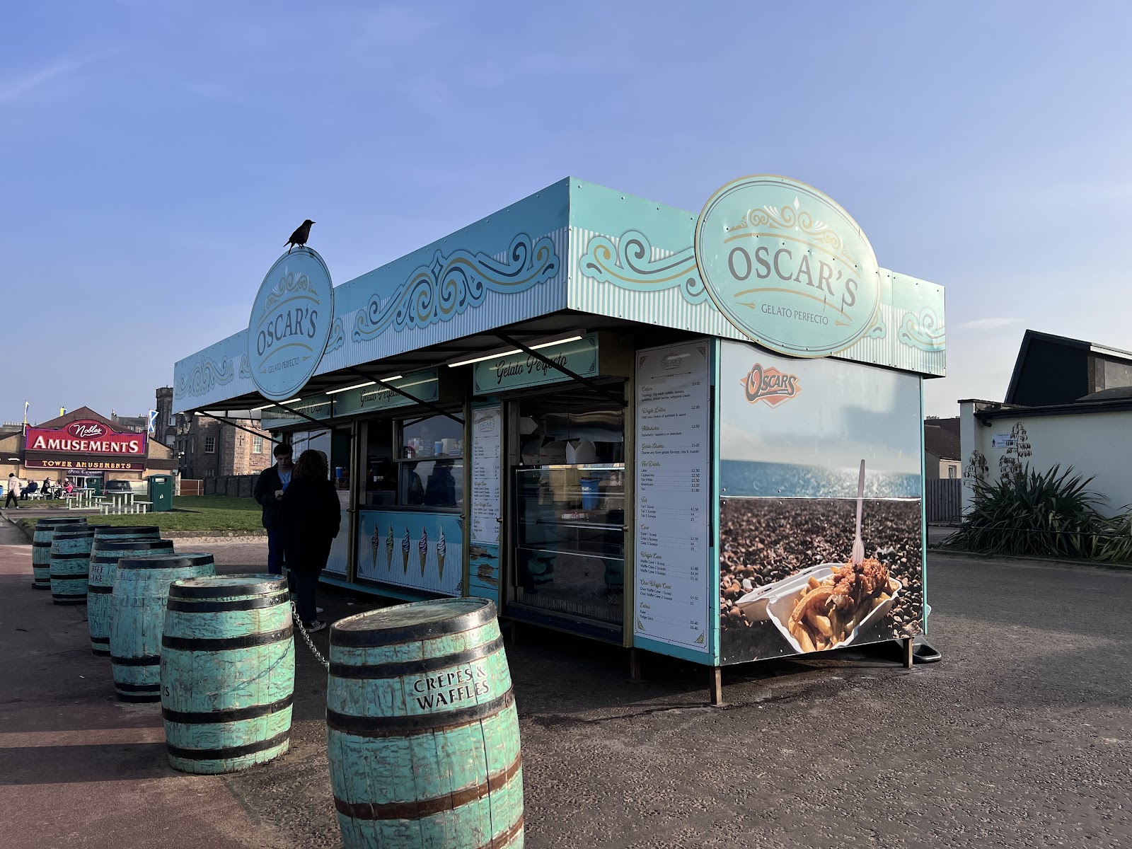 The pale blue Oscar's gelato kiosk on Portobello promenade, painted barrels around it.