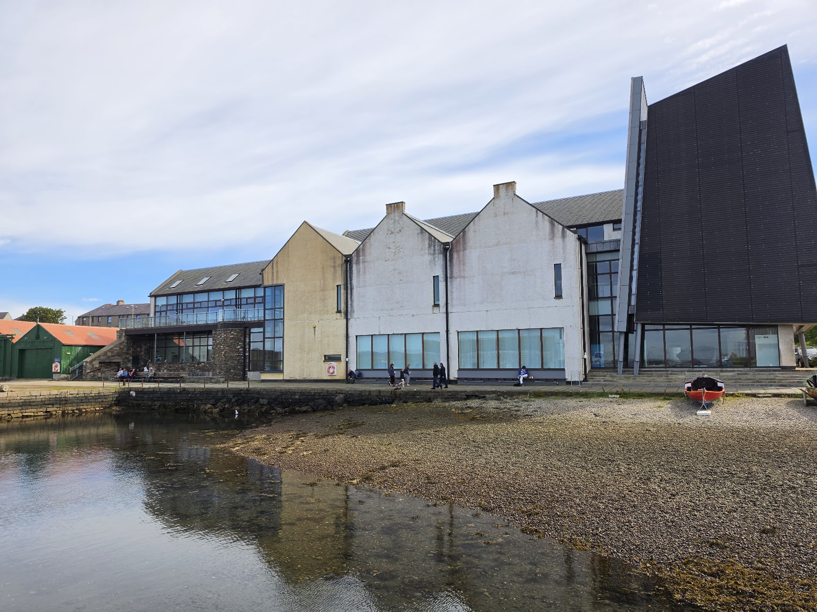 The Shetland Museum and Archives on Hay's Dock, its white gables and dark boat-hall tower reflected in the water.