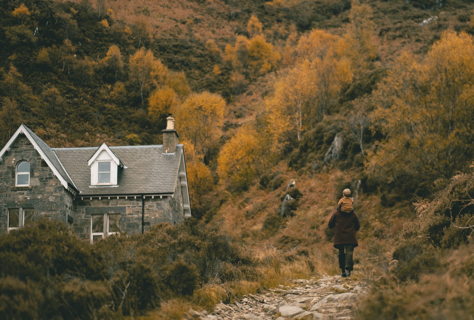 Eilean Shona, house on the wooded hillside with walker on the path