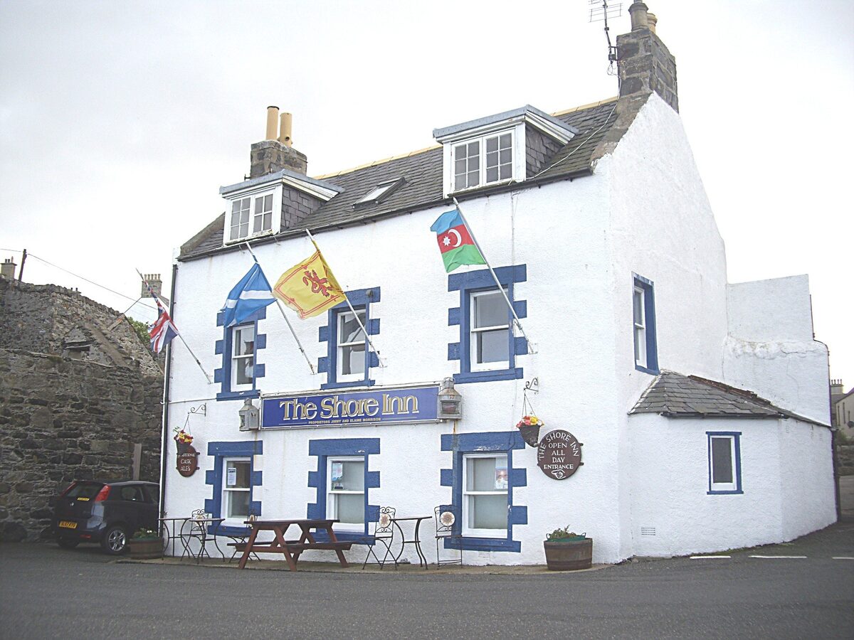 The white front of the Shore Inn on Portsoy's old harbour, flags over the door.