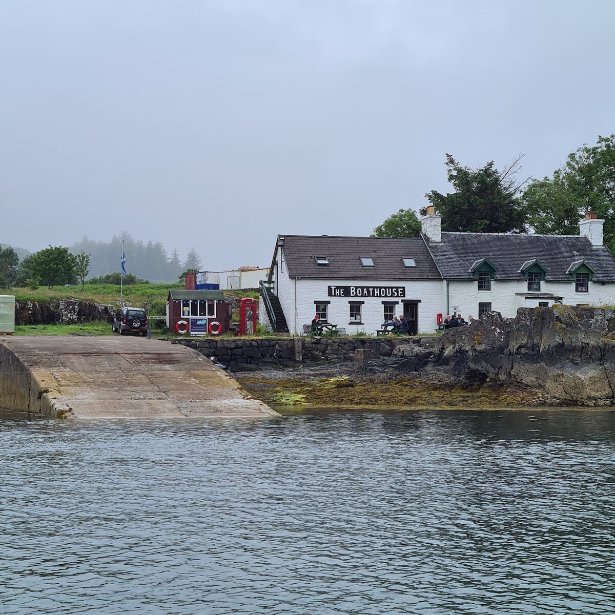 The Boathouse and the slipway on Ulva across the sound, white cottages under trees.