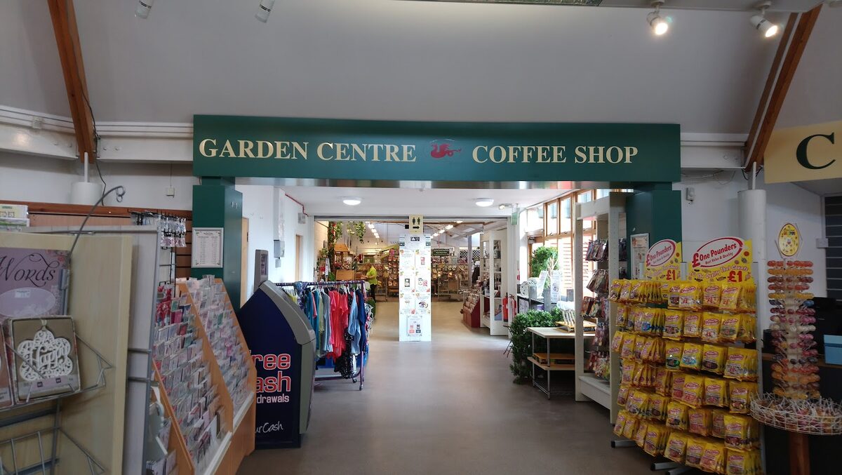 Green sign reading "Garden Centre Coffee Shop" above a shop entrance with £1 pounder displays