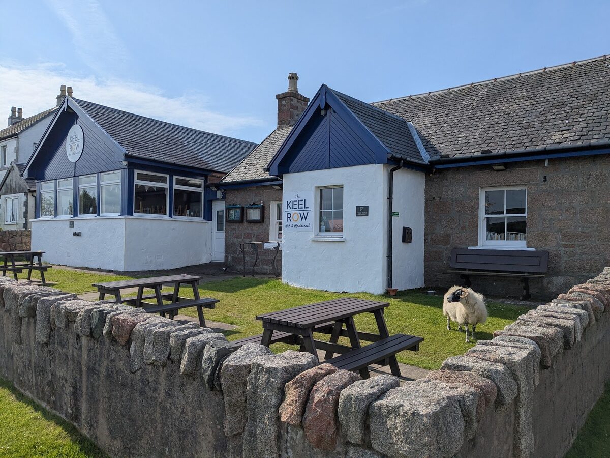The Keel Row in Fionnphort, low granite buildings with picnic benches behind a stone wall.