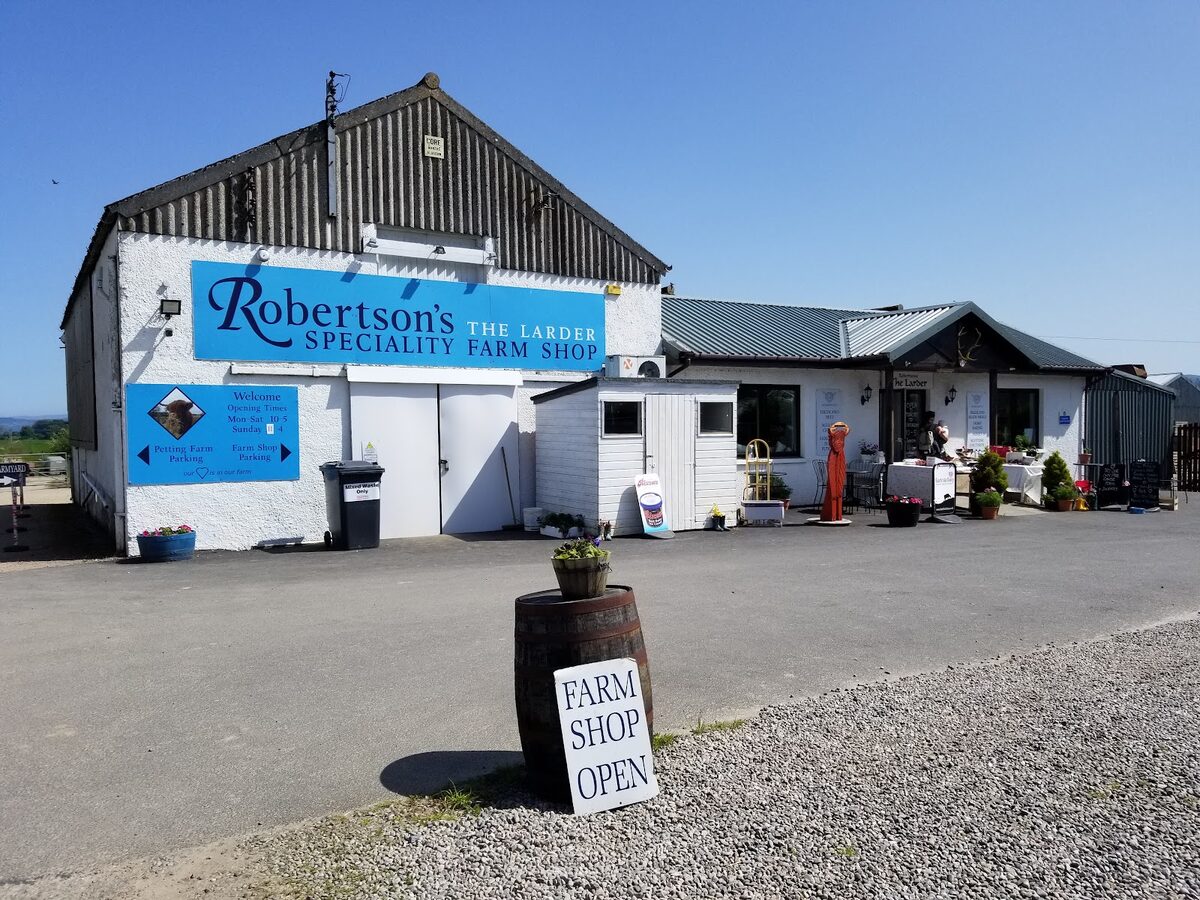 Robertson's Speciality Farm Shop near Beauly, a whitewashed building with a blue sign and a Farm Shop Open board on a barrel.