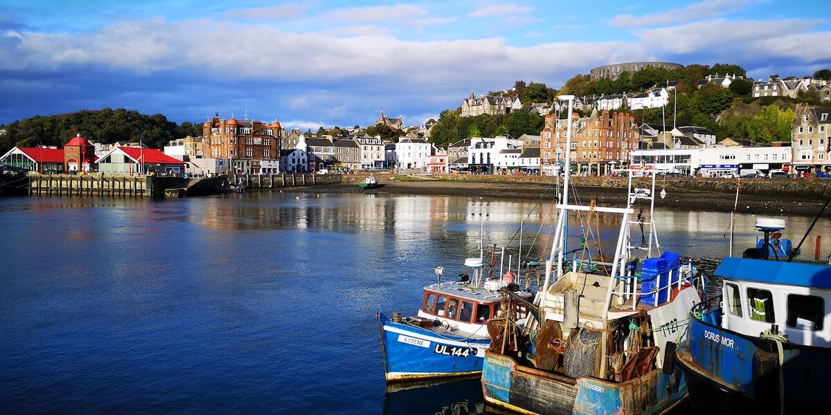 Fishing boats Kyrene and Dorus Mor moored in Oban harbour, McCaig's Tower above the town