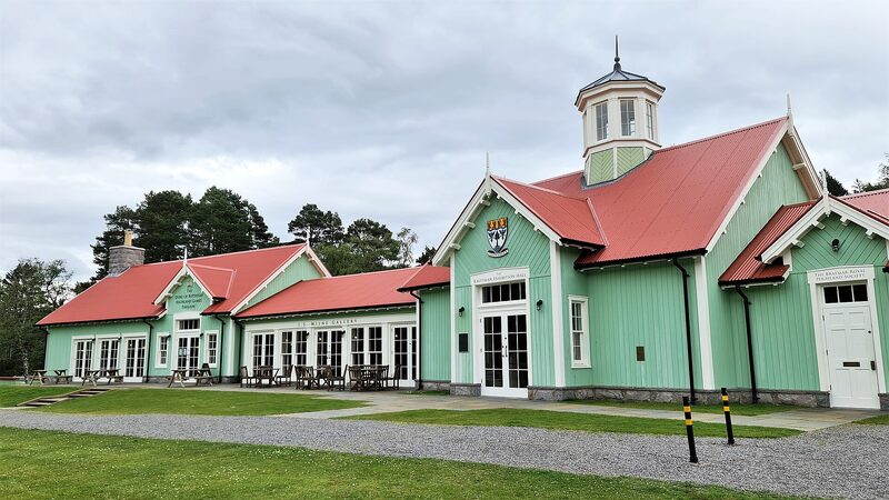 The Duke of Rothesay Highland Games Pavilion at Braemar, green timber under red roofs and a white clock tower.