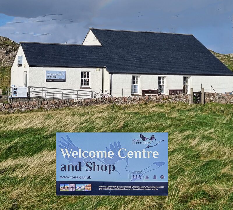 The Iona Community's Welcome Centre and Shop, a low white building with its sign on the grass in front.