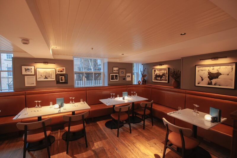 The dining room at Luckenbooths, leather banquettes and framed pictures under warm light.