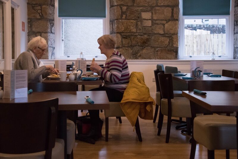 Diners at tables in the café's stone-walled room.