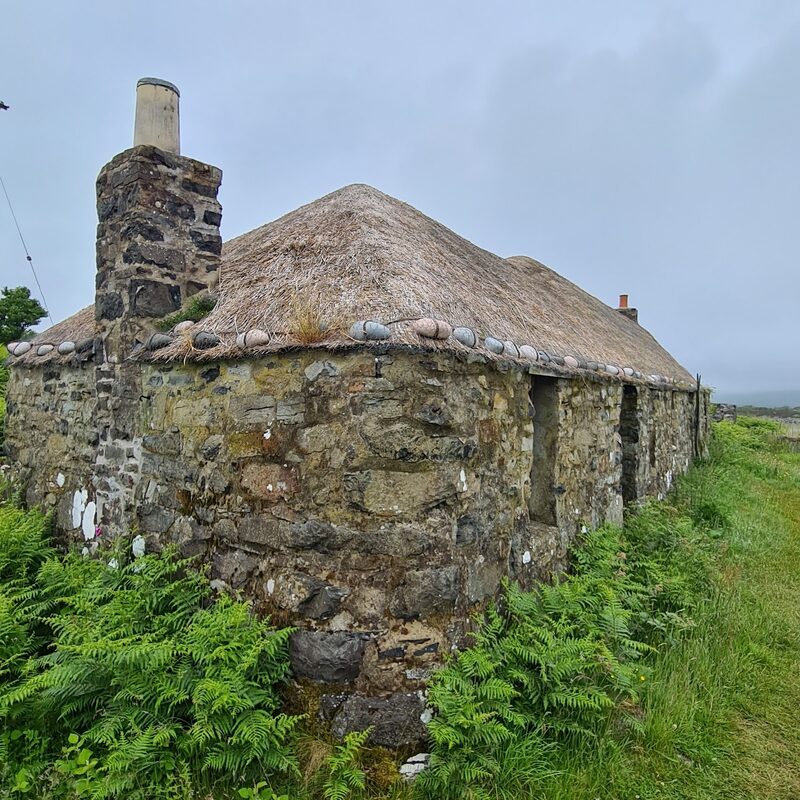 Sheila's Cottage on Ulva, a restored thatched croft house of stone among ferns.