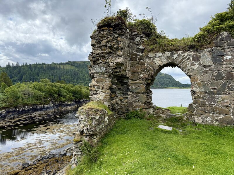 A broken stone arch of Strome Castle on its grassy bluff above Loch Carron.