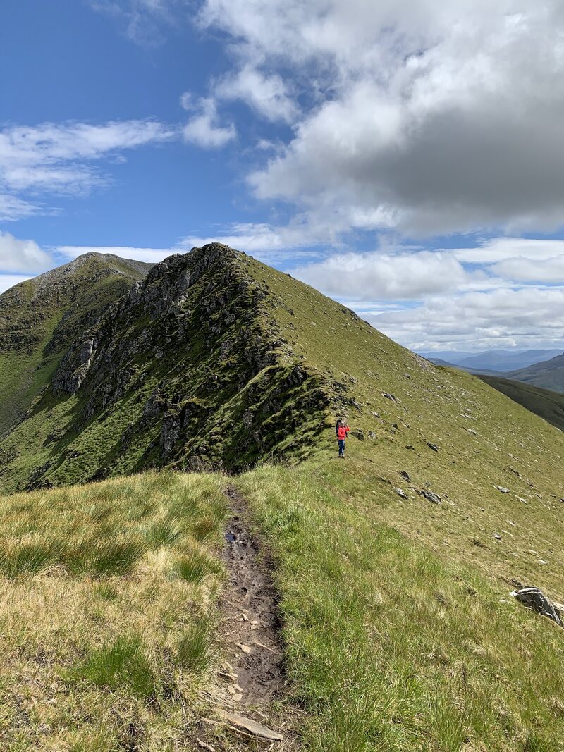A narrow grassy ridge with a path, rising to a rocky top on Sgùrr a' Bhealaich Dheirg.