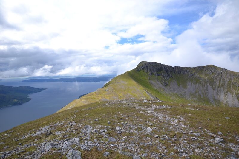 A grassy crest running to a craggy top, with a sea loch far below.