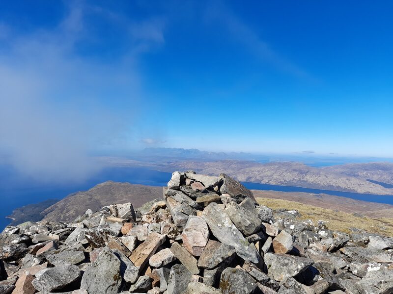 A cairn of piled stones high on Beinn Sgritheall, with the loch and far hills behind.