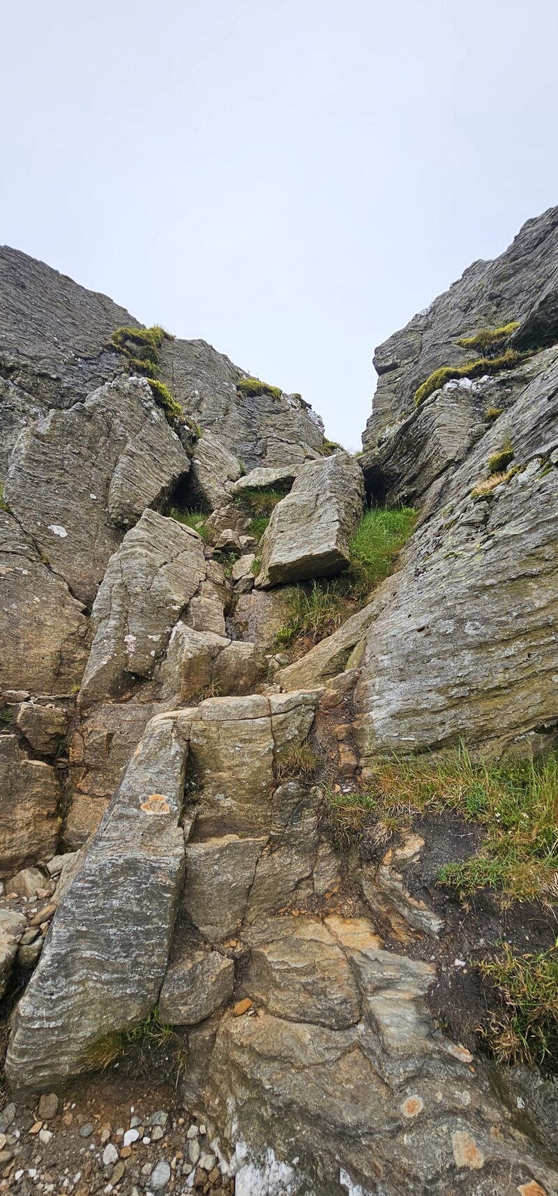 Steps of bare rock between crags on the way up Ben Vane, under a white sky.