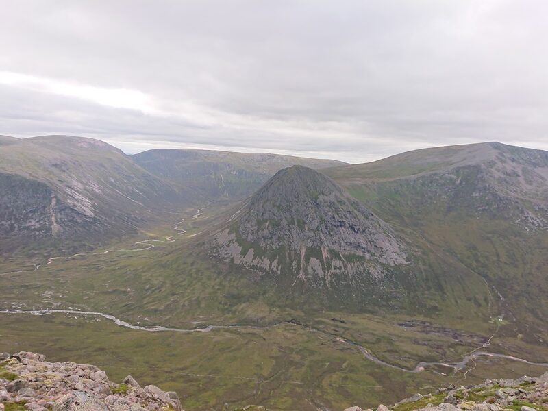 The Devil's Point seen from high on the far side of the glen, a dark cone of rock between two valleys with a river looping across the floor.