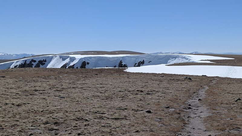A path across the bare plateau towards a corrie rim still holding deep snow.