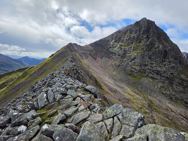 The boulder crest of the Càrn Mòr Dearg arête curving round to the dark face of Ben Nevis.