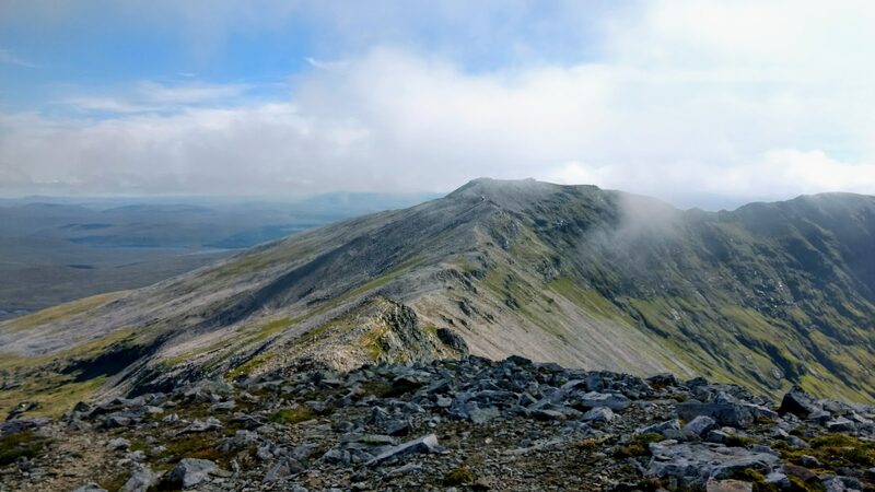 Broken quartzite underfoot and a long ridge rising to a summit in drifting cloud, on the round of Ben More Assynt and Conival.
