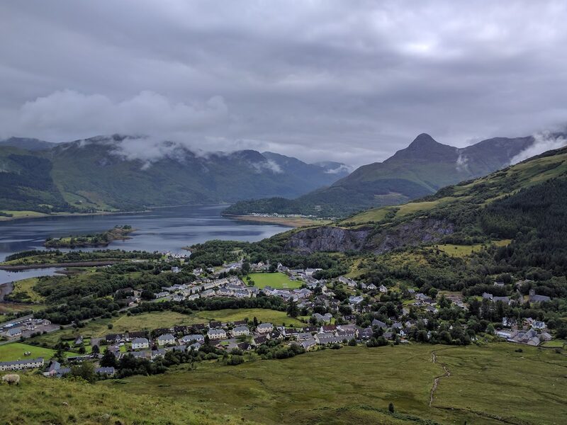 Ballachulish and Loch Leven from the hillside above the village, with a pointed peak across the water under low cloud.