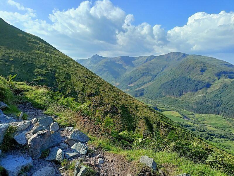 A rocky stretch of path with the glen and its hills below.