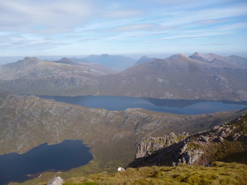 Two lochs and a crowd of rocky hills beyond them, from the grass and crags at the top of Slioch.