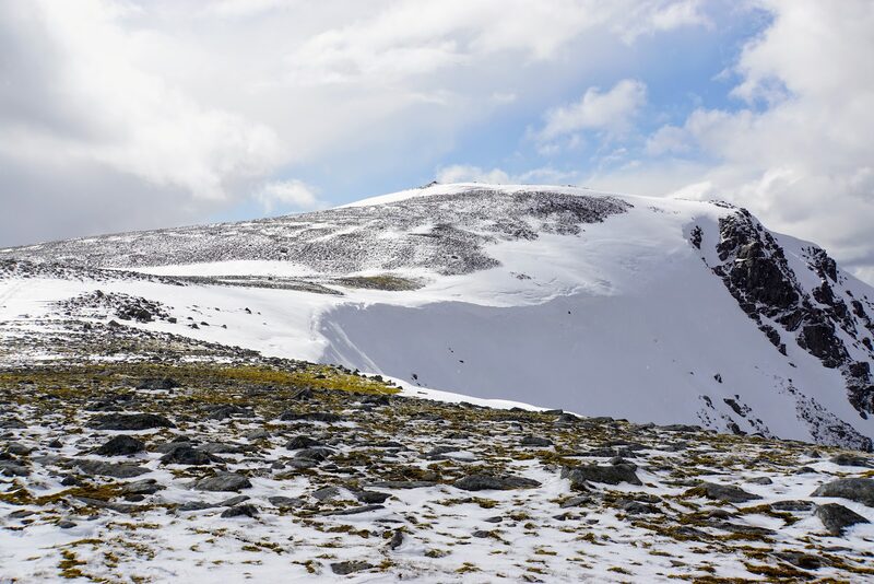 Beinn a' Chlachair's corrie from its rim under snow, with the summit dome on the skyline and crags on the far wall.