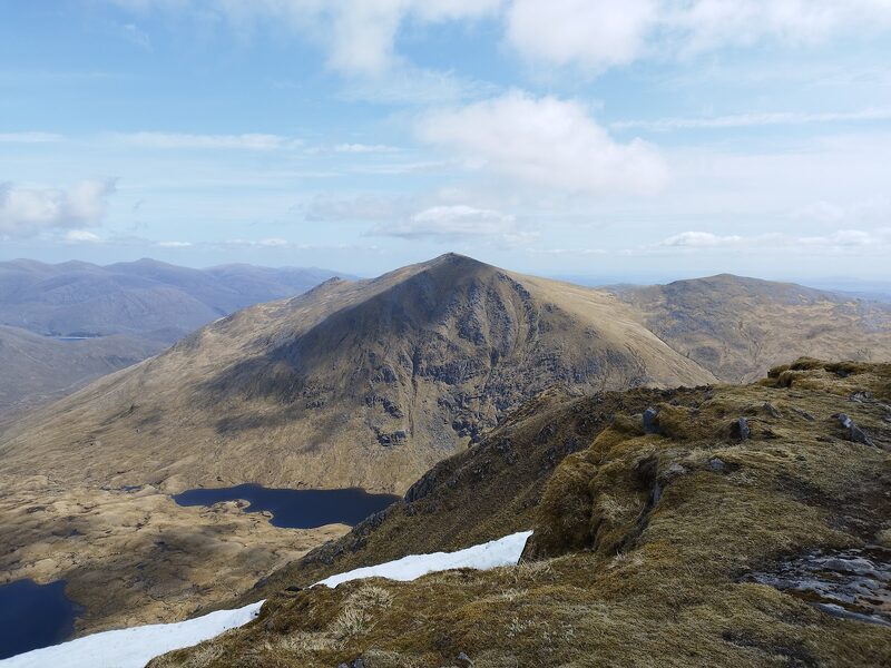 The pointed summit of Sgurr na Lapaich seen along the ridge, with dark crags on its face and two lochans in the corrie below.