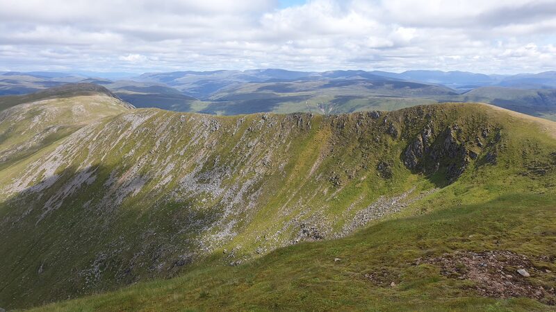 The wide grassy corrie of Sròn a' Choire Ghairbh, seen from its rim, hills ranged beyond.