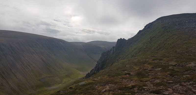 A crag at the lip of a deep glen under heavy cloud.