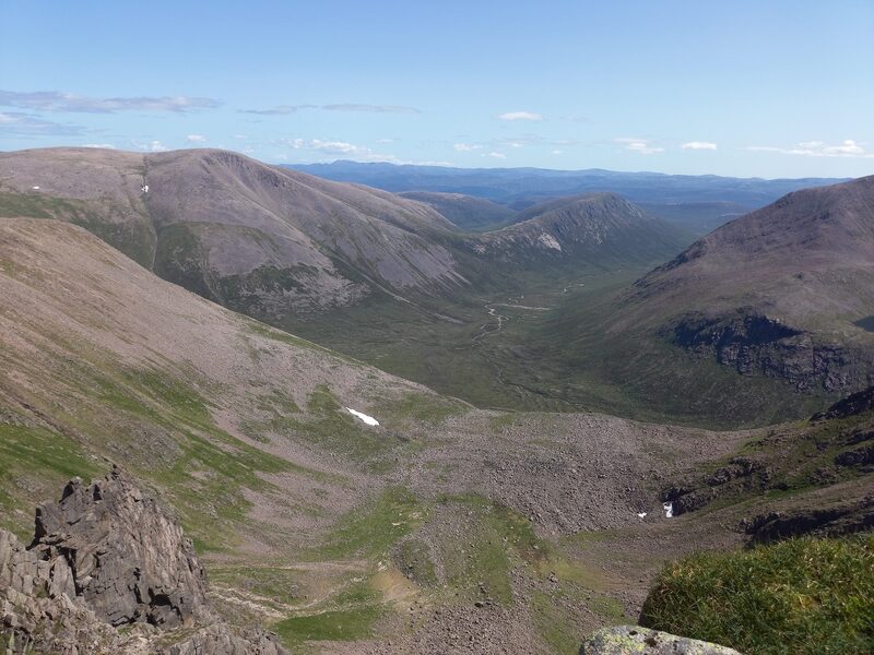 A long glen running away between high, bare hills, seen from the stony upper slopes on a clear day.
