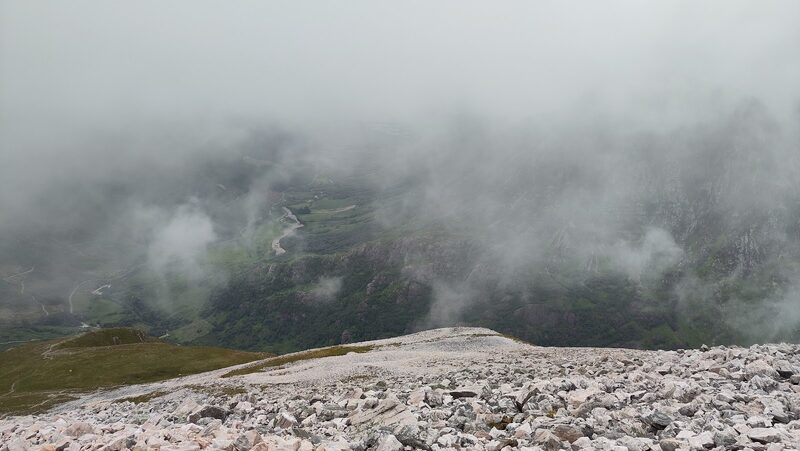 Pale broken stones on the upper hill with cloud pouring through the glen below.