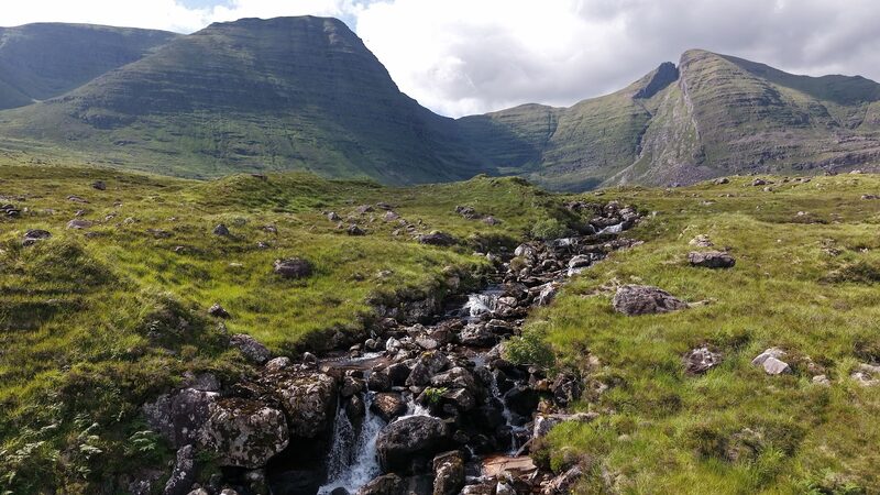 Beinn Alligin's two tops above a burn on the moor, the right-hand one cut by a great black cleft.